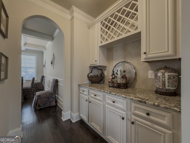 interior space with decorative backsplash, arched walkways, dark wood finished floors, beam ceiling, and ornamental molding