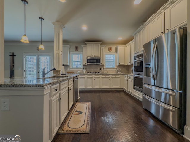 kitchen with white cabinets, light stone countertops, appliances with stainless steel finishes, a sink, and dark wood-style floors
