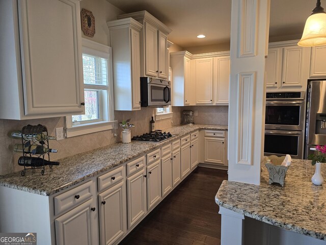 kitchen with appliances with stainless steel finishes, light stone countertops, and white cabinetry