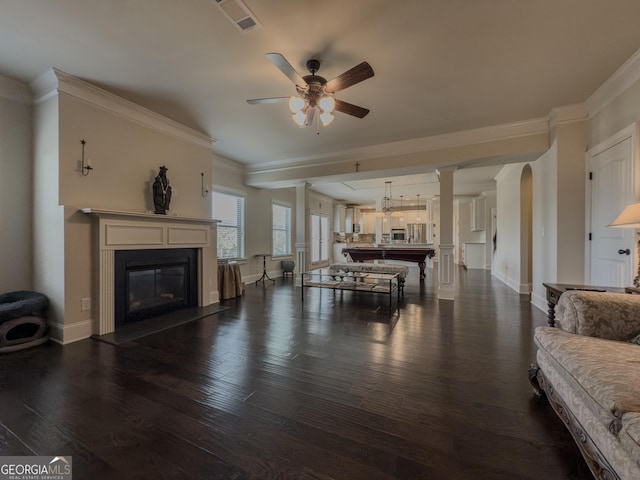 living room with crown molding, ceiling fan, a glass covered fireplace, baseboards, and dark wood-style floors