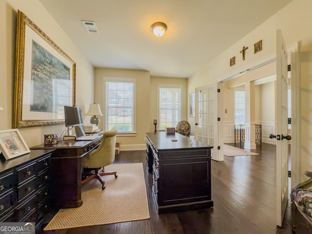 office featuring visible vents, a wainscoted wall, and dark wood-style floors