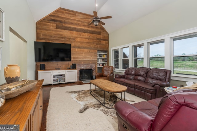 1725 Watermelon Rd, Tennille, GA 31089 - living room with high vaulted ceiling, wooden walls, a brick fireplace, ceiling fan, and dark wood-type flooring