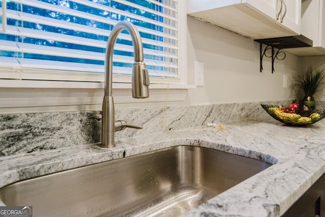 710 Bluebird Dr SE, Conyers, GA 30094 - room details with light stone counters, a sink, and white cabinetry