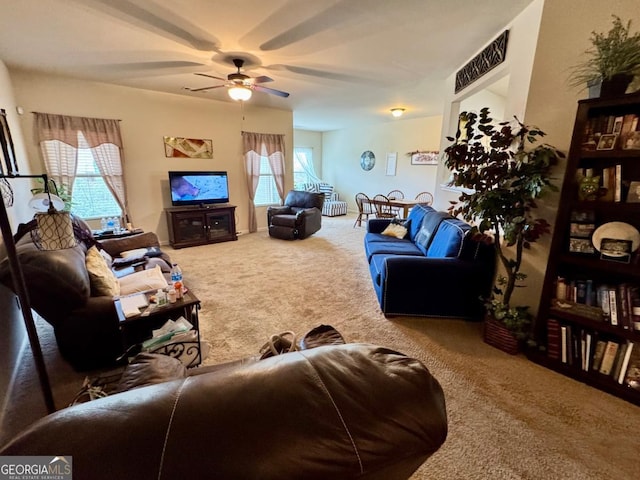living area with a wealth of natural light, carpet floors, and a ceiling fan