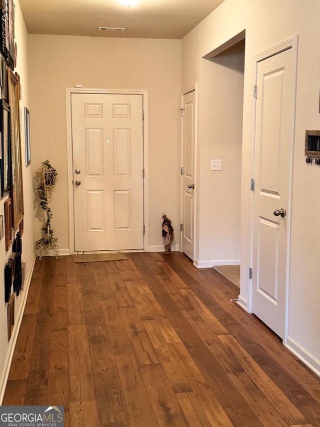 hall featuring dark wood-style floors, baseboards, and visible vents