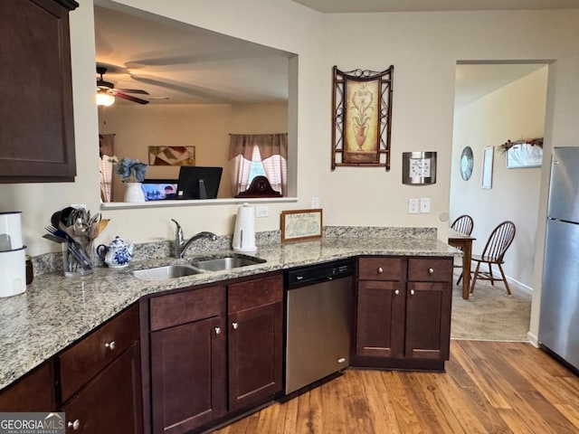kitchen featuring light stone counters, a sink, a ceiling fan, appliances with stainless steel finishes, and light wood-style flooring