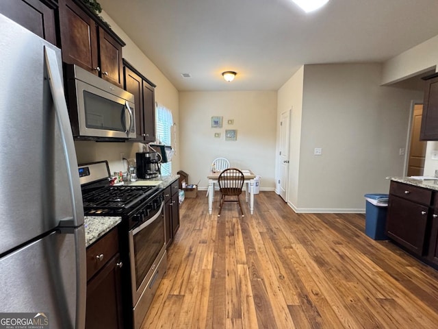 kitchen featuring dark brown cabinets, baseboards, hardwood / wood-style floors, and stainless steel appliances