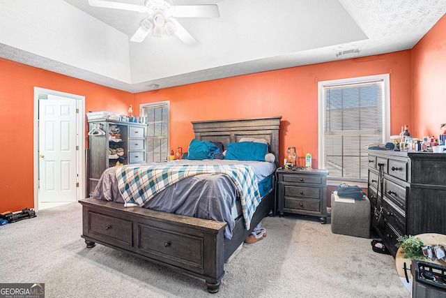 carpeted bedroom with a raised ceiling, ceiling fan, and visible vents