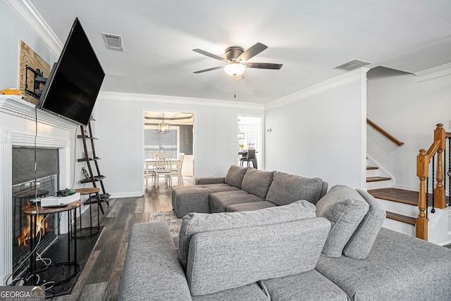 living area featuring a ceiling fan, dark wood-style floors, visible vents, and stairway
