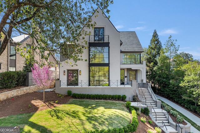 view of front of house with stucco siding, a front yard, and a balcony