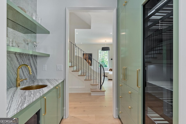 bar with indoor wet bar, tasteful backsplash, stairway, a sink, and light wood finished floors