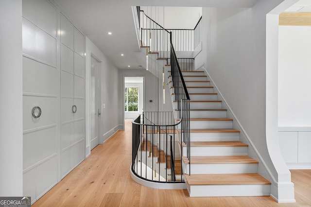 stairway featuring wood finished floors, baseboards, and recessed lighting