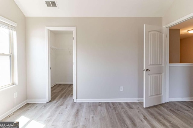 6399 Woodwell Dr, Union City, GA 30291 - unfurnished bedroom featuring multiple windows, light wood-style flooring, a closet, and a walk in closet