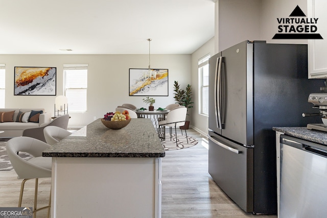 6399 Woodwell Dr, Union City, GA 30291 - kitchen with stainless steel appliances, a breakfast bar, light wood-type flooring, a kitchen island, and white cabinets