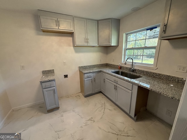 3685 Rice Mill Rd, Macon, GA 31206 - kitchen with a sink, gray cabinetry, stone counters, light marble finish flooring, and baseboards