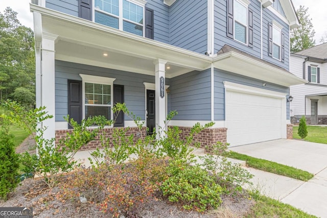 9061 Jim Purcell Dr, Covington, GA 30014 - property entrance with an attached garage, a porch, brick siding, and driveway