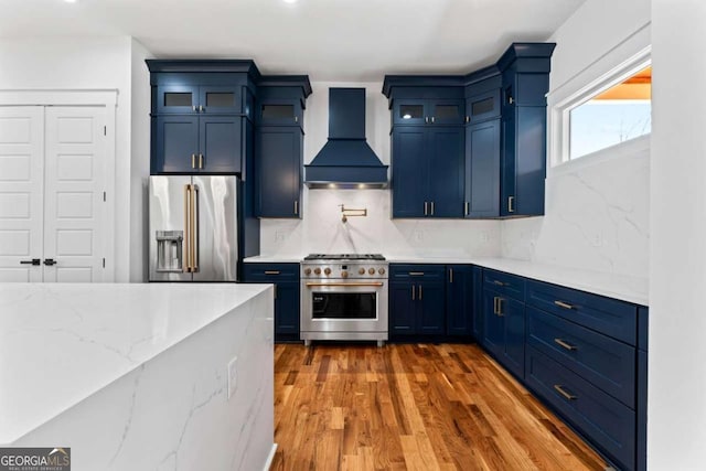 387 S Howard St SE, Atlanta, GA 30317 - kitchen featuring high quality appliances, custom exhaust hood, blue cabinetry, wood finished floors, and glass insert cabinets
