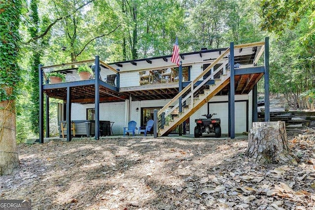 rear view of property featuring stairway, a deck, and an attached garage