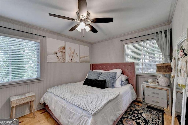 bedroom featuring multiple windows, crown molding, wood finished floors, and ceiling fan