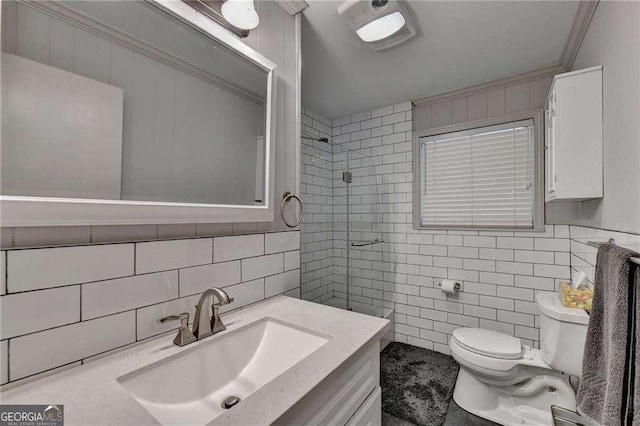 bathroom featuring a tile shower, crown molding, toilet, vanity, and tile walls