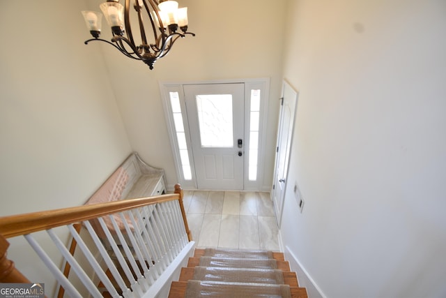 entrance foyer with baseboards, an inviting chandelier, stairs, and a towering ceiling
