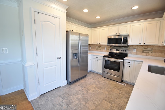 kitchen with crown molding, a sink, stainless steel appliances, recessed lighting, and backsplash