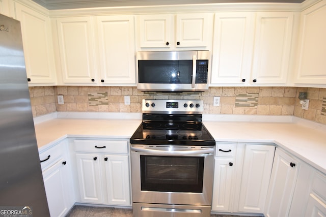 kitchen featuring white cabinets, backsplash, appliances with stainless steel finishes, and light countertops