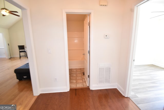 hallway featuring baseboards, visible vents, and wood finished floors