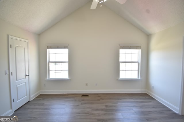 spare room with wood finished floors, ceiling fan, high vaulted ceiling, and baseboards