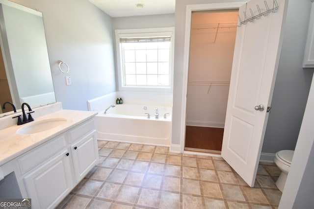 full bath featuring baseboards, toilet, vanity, a walk in closet, and a garden tub