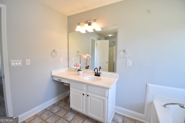 full bath featuring baseboards, a textured ceiling, a bathing tub, and vanity