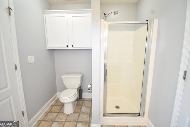 bathroom with baseboards, a stall shower, and toilet