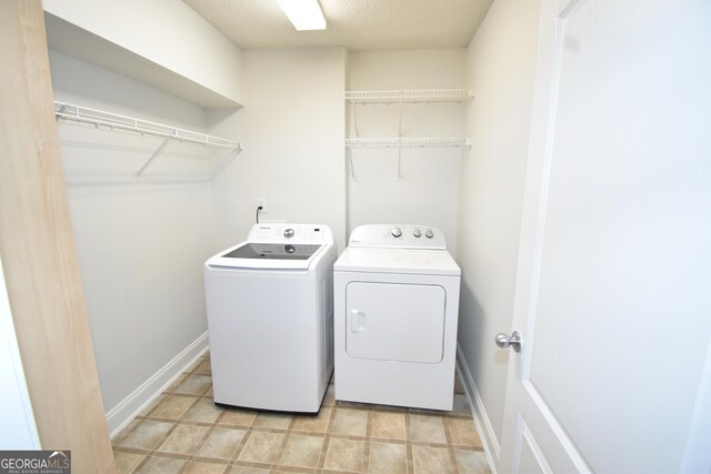 clothes washing area featuring washing machine and dryer, a textured ceiling, laundry area, and baseboards