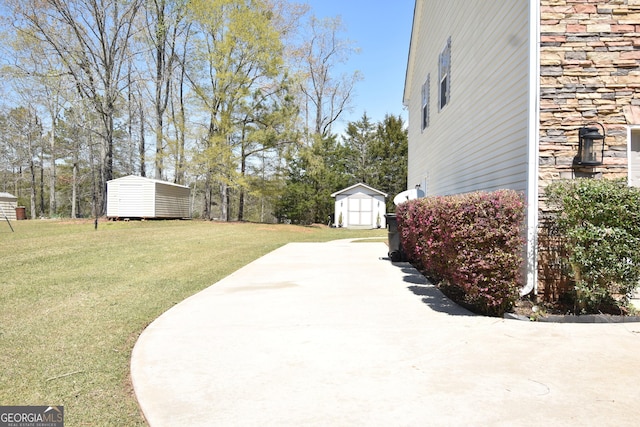 view of yard featuring concrete driveway, a shed, and an outbuilding