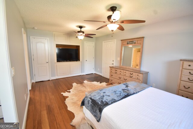 bedroom with dark wood-style floors, a textured ceiling, ceiling fan, and baseboards