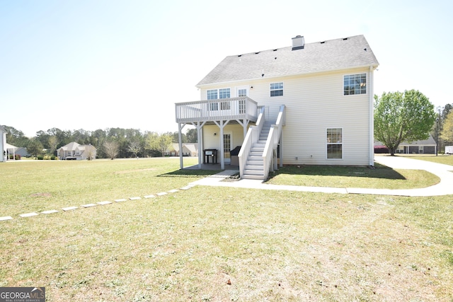 rear view of house featuring a lawn, a chimney, stairs, and a wooden deck