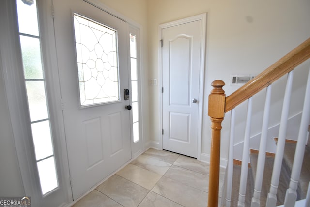 foyer entrance featuring stairway, visible vents, and baseboards