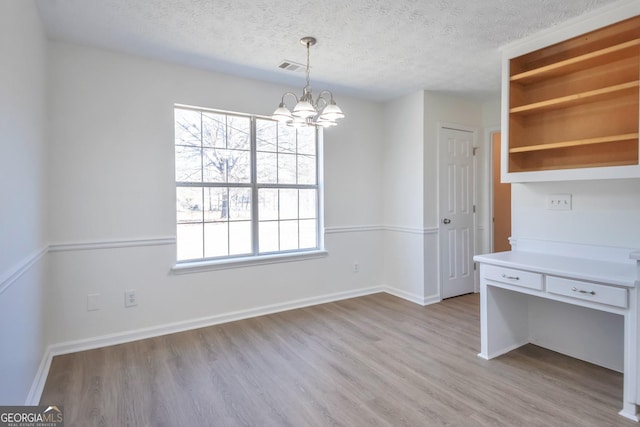 4785 Beaver Rd, Loganville, GA 30052 - unfurnished dining area with a chandelier, light wood finished floors, a textured ceiling, baseboards, and visible vents