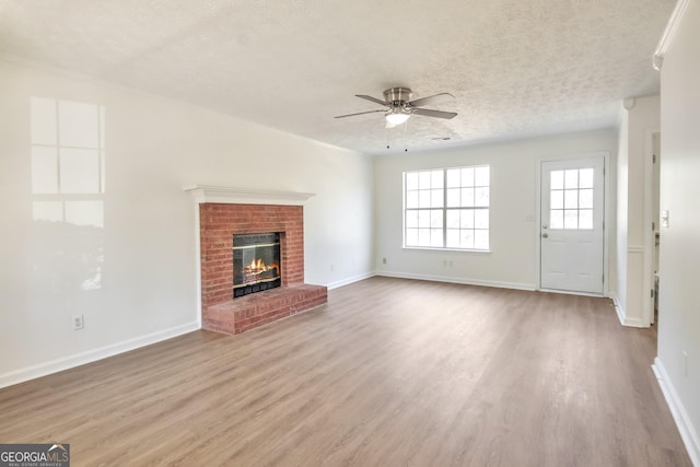 4785 Beaver Rd, Loganville, GA 30052 - unfurnished living room featuring baseboards, a textured ceiling, a ceiling fan, a fireplace, and wood finished floors