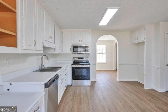 4785 Beaver Rd, Loganville, GA 30052 - kitchen with arched walkways, white cabinets, a sink, and appliances with stainless steel finishes