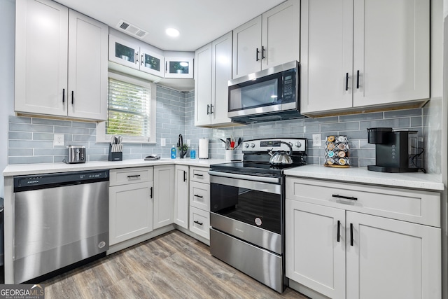 2535 Judson Ave, East Point, GA 30344 - kitchen with visible vents, decorative backsplash, light wood-style floors, light countertops, and appliances with stainless steel finishes