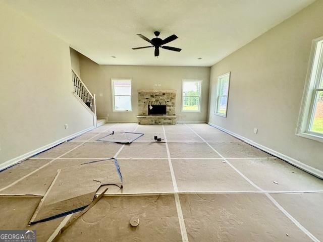 27 Sagebrook Ln Lot 1, Newnan, GA 30263 - unfurnished living room featuring healthy amount of natural light, a ceiling fan, a stone fireplace, and baseboards