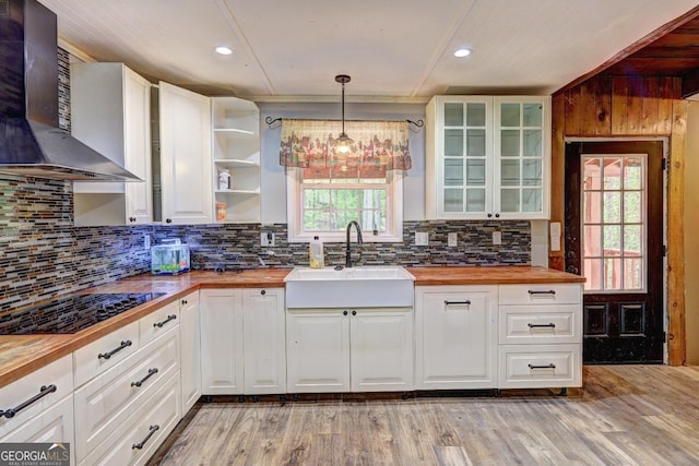 12 John Boy Trl, Newnan, GA 30263 - kitchen with butcher block counters, a sink, black electric stovetop, wall chimney exhaust hood, and light wood-style floors