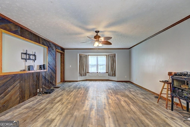 12 John Boy Trl, Newnan, GA 30263 - unfurnished living room featuring ornamental molding, wood walls, ceiling fan, wood finished floors, and a textured ceiling