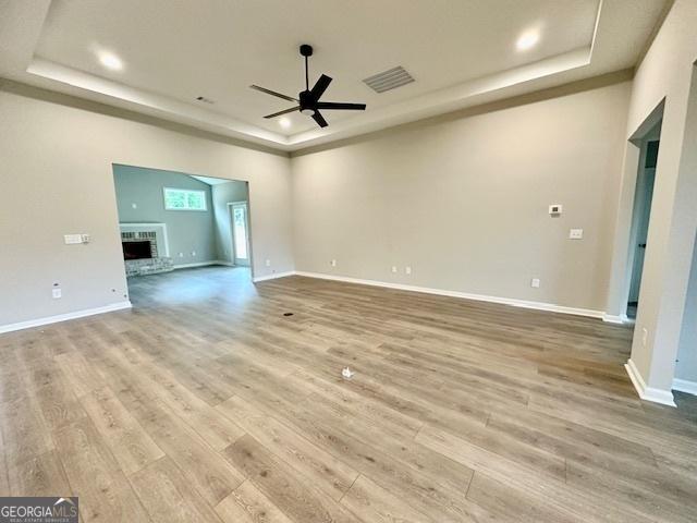 149 Sagebrook Ln Lot 8, Newnan, GA 30263 - empty room featuring a tray ceiling, a ceiling fan, wood finished floors, a brick fireplace, and baseboards