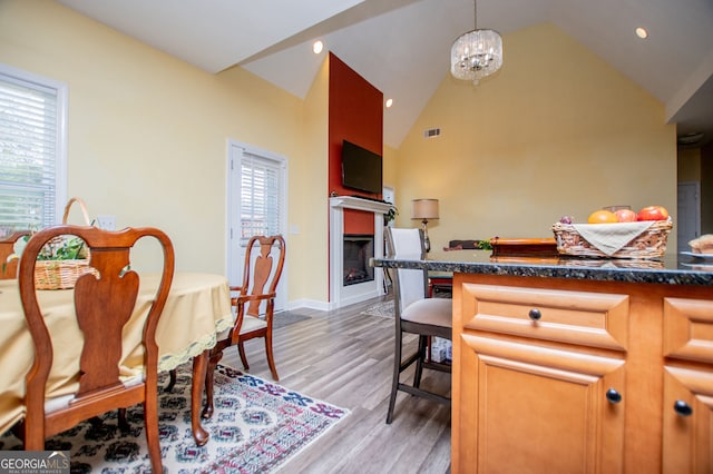 207 Meadow Lake Dr, Carrollton, GA 30116 - dining area featuring a fireplace, vaulted ceiling, light wood-style floors, a chandelier, and baseboards