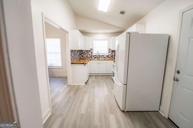 107 Griffith St, Winder, GA 30680 - kitchen featuring white cabinets, a sink, light wood finished floors, freestanding refrigerator, and vaulted ceiling