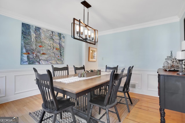 1135 Parkview Way, Lilburn, GA 30047 - dining area featuring a notable chandelier, a wainscoted wall, light wood-style flooring, a decorative wall, and ornamental molding
