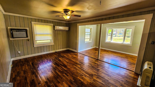 unfurnished bedroom featuring a wall unit AC, an AC wall unit, baseboards, and wood finished floors