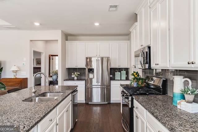 2910 Bishopstone Way, Cumming, GA 30040 - kitchen with dark stone counters, white cabinetry, visible vents, appliances with stainless steel finishes, and a sink